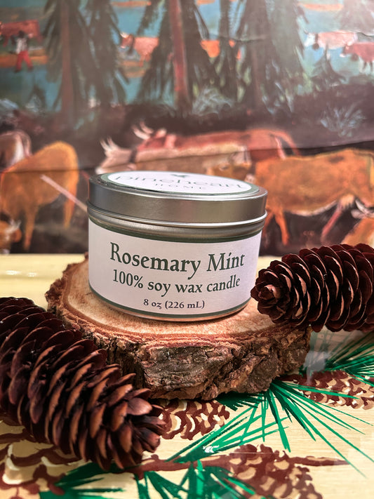 Rosemary Mint soy wax candle in an 8 oz. tin sitting on a piece of wood with pinecones.